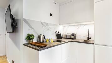 Eine moderne Küche mit weißen Schränken, einer Marmor-Spritzschutzleiste, einem eingebauten Backofen, einer Kaffeemaschine und einem Toaster.
