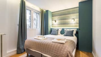 Ein modernes Schlafzimmer mit Bett, Vorhängen, Heizkörper und einem gemusterten Kopfteil.