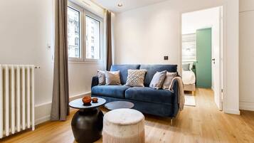 Ein modernes Wohnzimmer mit einem blauen Sofa, einem runden Couchtisch und einem kleinen Hocker.