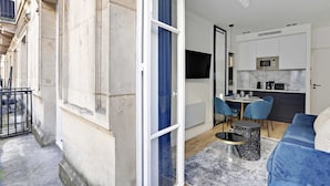 A modern apartment with a dining area, kitchen, and a balcony.