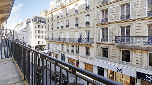 A multi-story building with balconies, storefronts, and a pedestrian walkway.