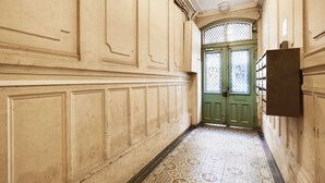 A hallway with ornate paneling and patterned floor tiles leading to a green door with glass panels. - Cocooning studio - 2P - Center of Paris (Paris)