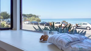 Vista desde la ventana de un hotel, con vista a un estacionamiento con varios autos y una playa.