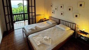 A room with two beds, a balcony, and a view of greenery. - Eagle Nest Skiathos (Skiathos)