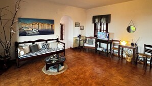 A cozy living room with a sofa, a coffee table, a TV, and a dining area with chairs and a table. - Eagle Nest Skiathos (Skiathos)