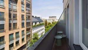 Un balcón con dos mesas redondas y vistas a edificios cercanos.