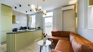 Una sala de estar moderna con un sofá marrón, una mesa de centro redonda y una cocina con una isla verde.