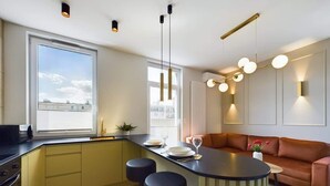Una cocina moderna con una isla central, taburetes de bar y una zona de estar con sofá.
