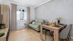 Una sala moderna con una mesa de comedor de madera, un sofá verde y una pequeña mesita auxiliar.