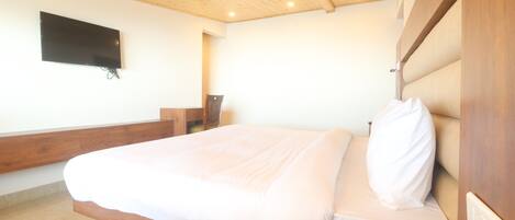 Une chambre à coucher avec un lit, un téléphone, un téléviseur fixé au mur et un plafond en bois.