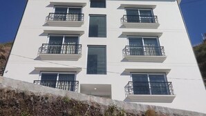 A multi-story building with balconies and large windows. - Hotel Mussoorie Heights (Dehradun)