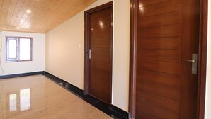 A spacious room with a polished floor, wooden ceiling, and two large wooden doors. - Hotel Mussoorie Heights (Dehradun)