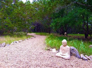 Une statue propice à la méditation, située dans un cadre naturel, avec un sentier de gravier.