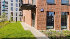 Un bâtiment moderne à la façade en briques, portant le numéro 22B, doté d’un balcon et d’un petit espace jardin.