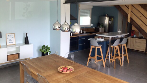 A modern kitchen with a central island, bar stools, and pendant lighting.