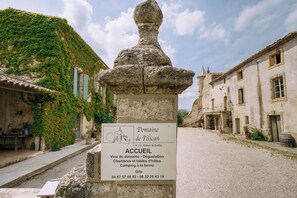 Un monumento in pietra con una targa in un contesto di villaggio, circondato da edifici con rampicanti.