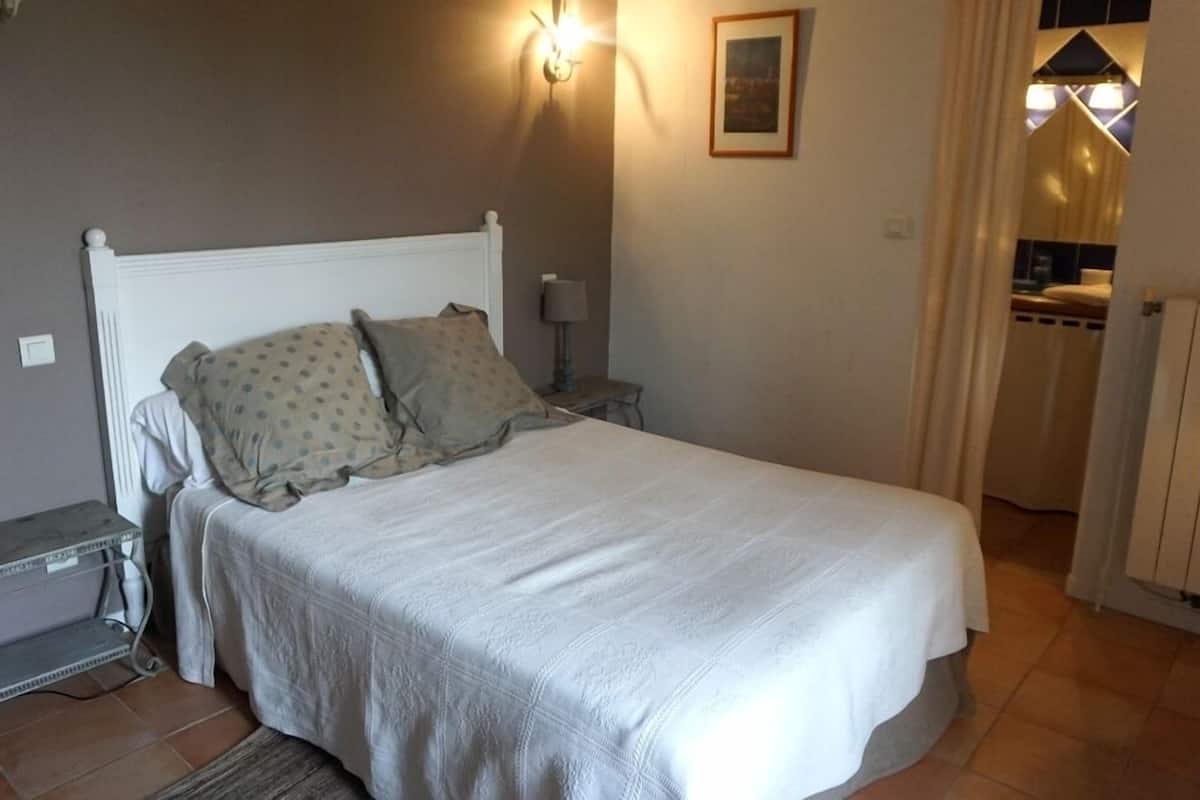 A bedroom with a bed, a nightstand, a lamp, and a wall-mounted light fixture.