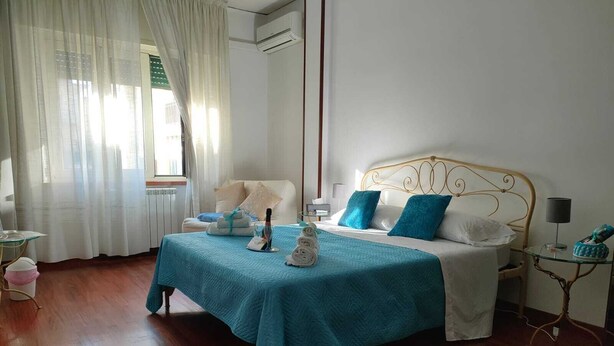 A bedroom with a bed, bedside tables, a lamp, and a window with curtains. - Tra Pirandello e Leopardi B&B (Naples)