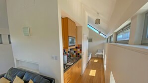 Um apartamento moderno com cozinha, sala de estar com sofá e um espaço pequeno para dormir.