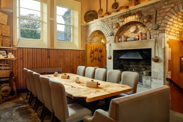 Un comedor con chimenea de ladrillo, mesa de madera y sillas.