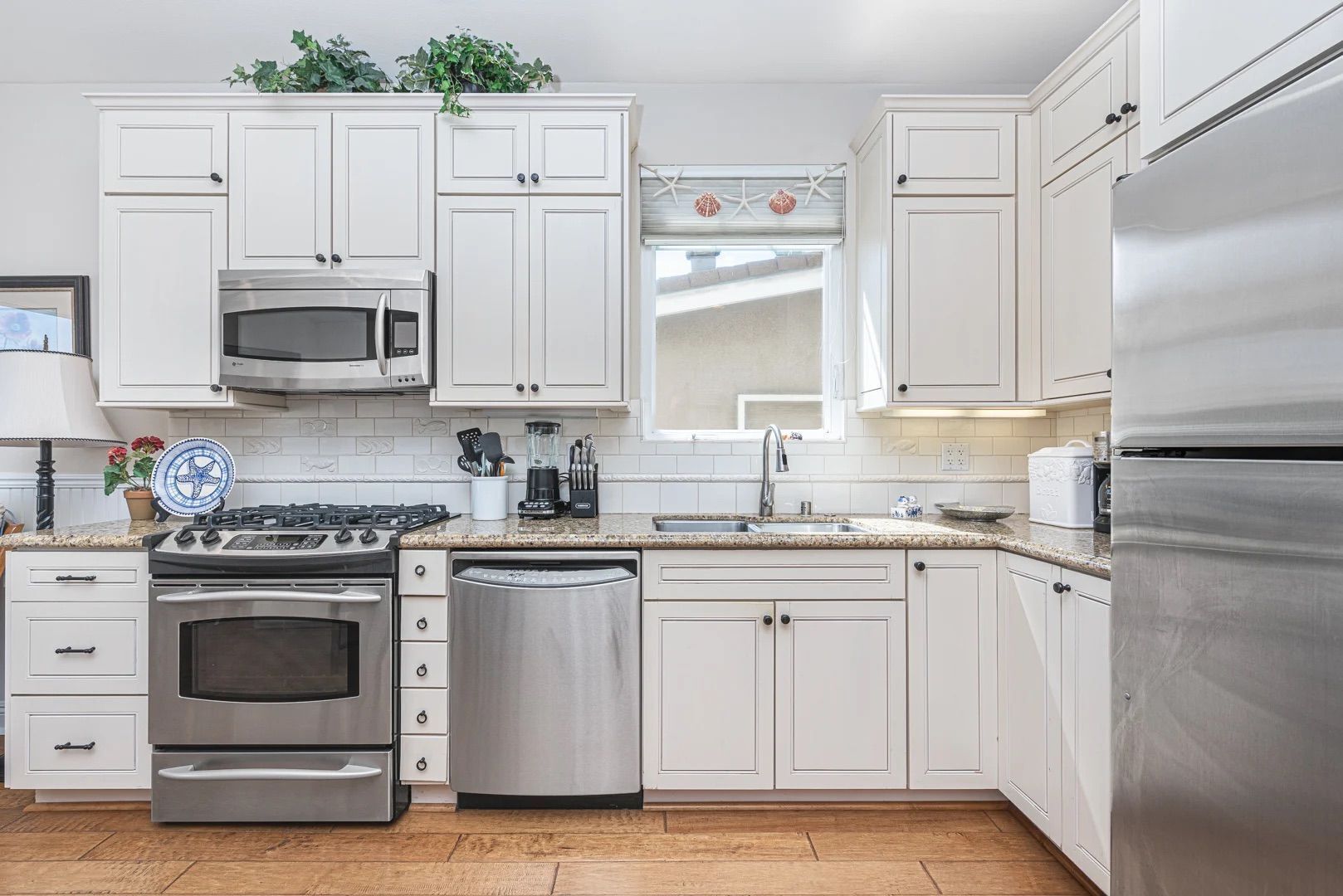 A modern kitchen with white cabinets, stainless steel appliances, and a granite countertop.