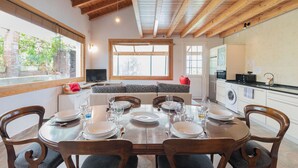 A dining area with a wooden table set for four, a sofa, and a kitchen with appliances. - Zeruhaundi - baskeyrentals (Biscay)