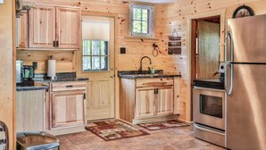Une cuisine de style rustique, avec des éléments en bois, comprenant un réfrigérateur en acier inoxydable, un évier et une fenêtre.