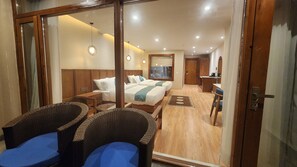 Une chambre d’hôtel avec deux lits, un bureau et des chaises en osier.