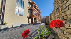 A narrow street with buildings featuring traditional architecture, a cobblestone path, and potted plants. - Hotel Ladakh Heights (Leh)