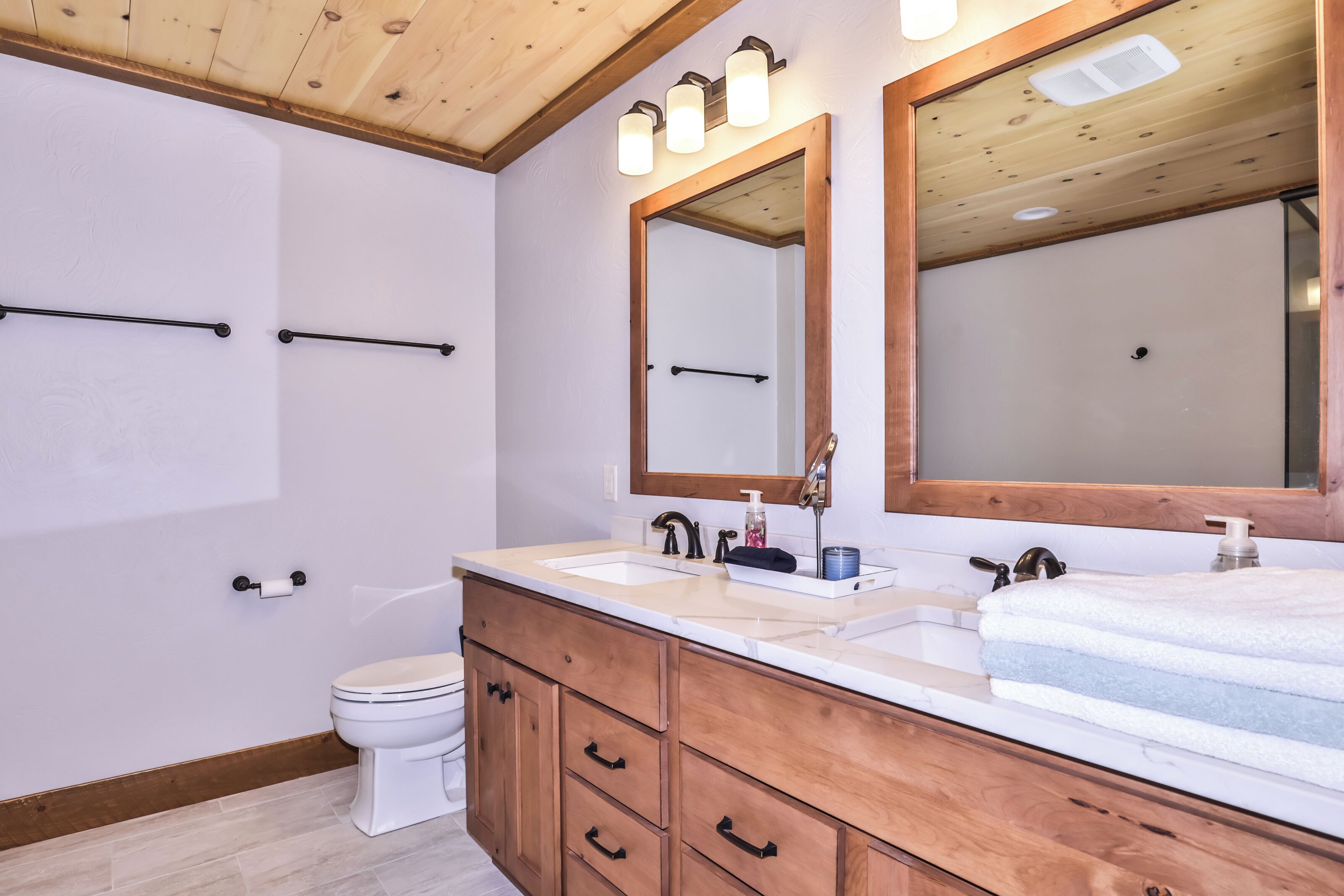A bathroom with wooden cabinets, a double sink vanity, and a large mirror.