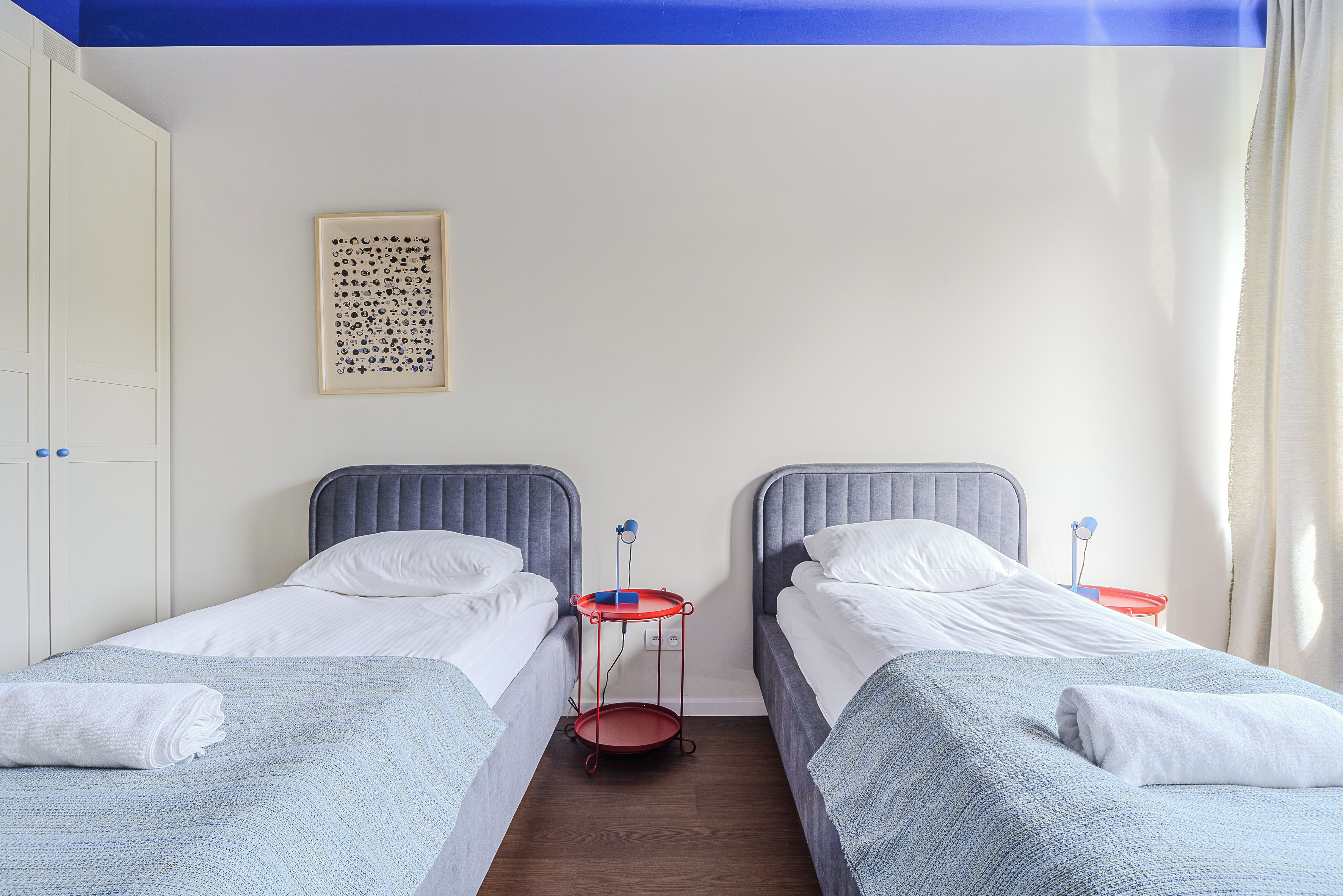 Een slaapkamer met twee bedden, een nachtkastje, een kunstwerk aan de muur en een garderobe.