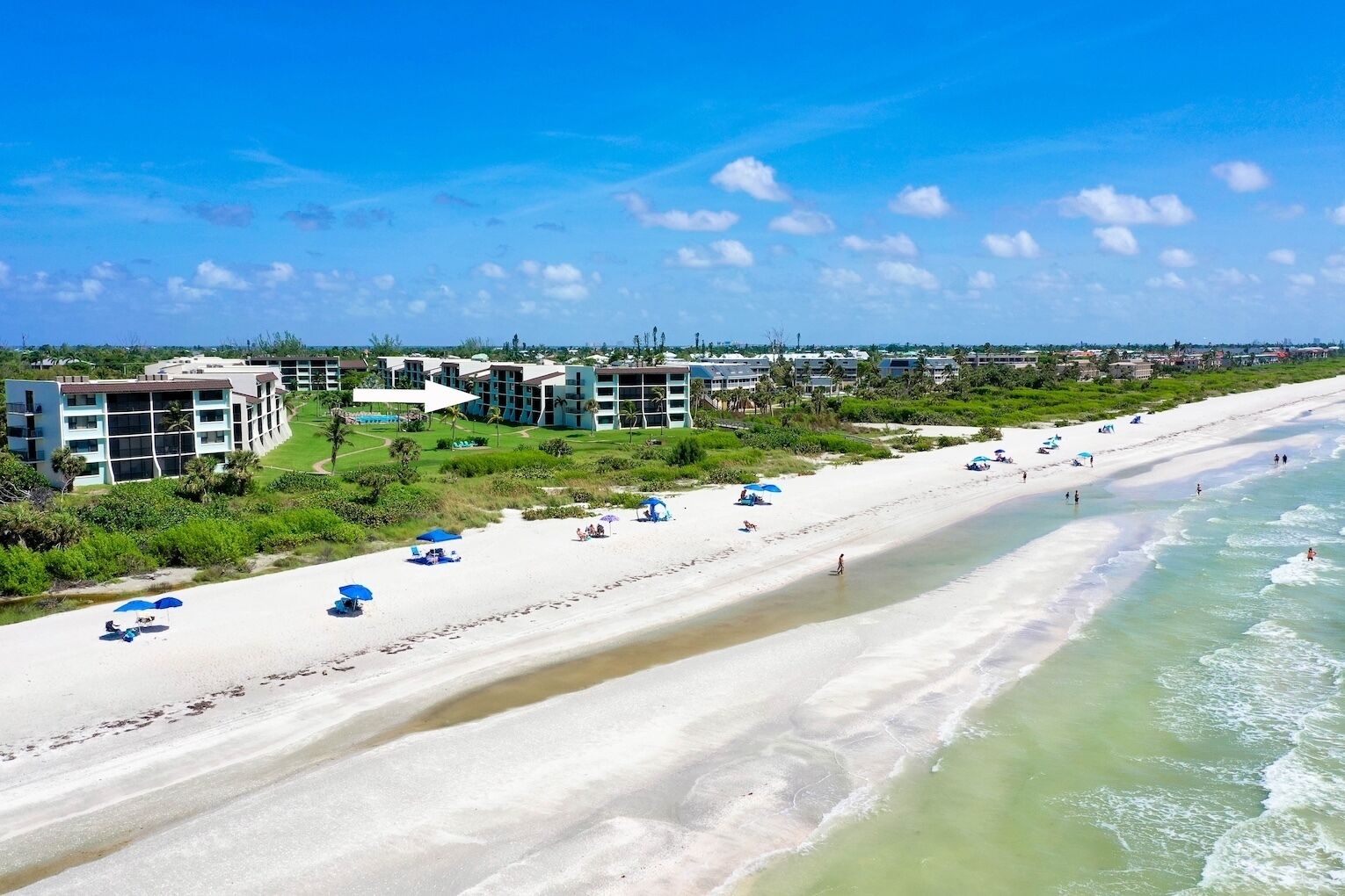 A beach resort with multiple buildings, a sandy beach, and ocean views.