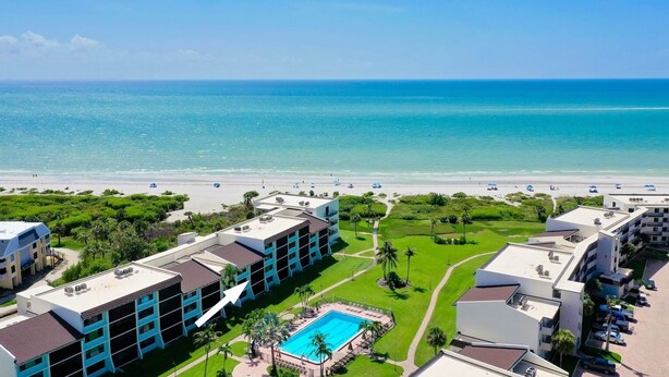 Un hotel con piscina, vista sulla spiaggia e diversi edifici.