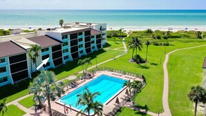 Un hotel con piscina, vista sulla spiaggia e prato ben curato.
