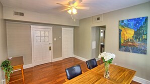 A dining room with a wooden table, chairs, a ceiling fan, and a painting on the wall. - Cafe Terrace at TG Park | Fenced Backyard+W/D (Saint Louis)