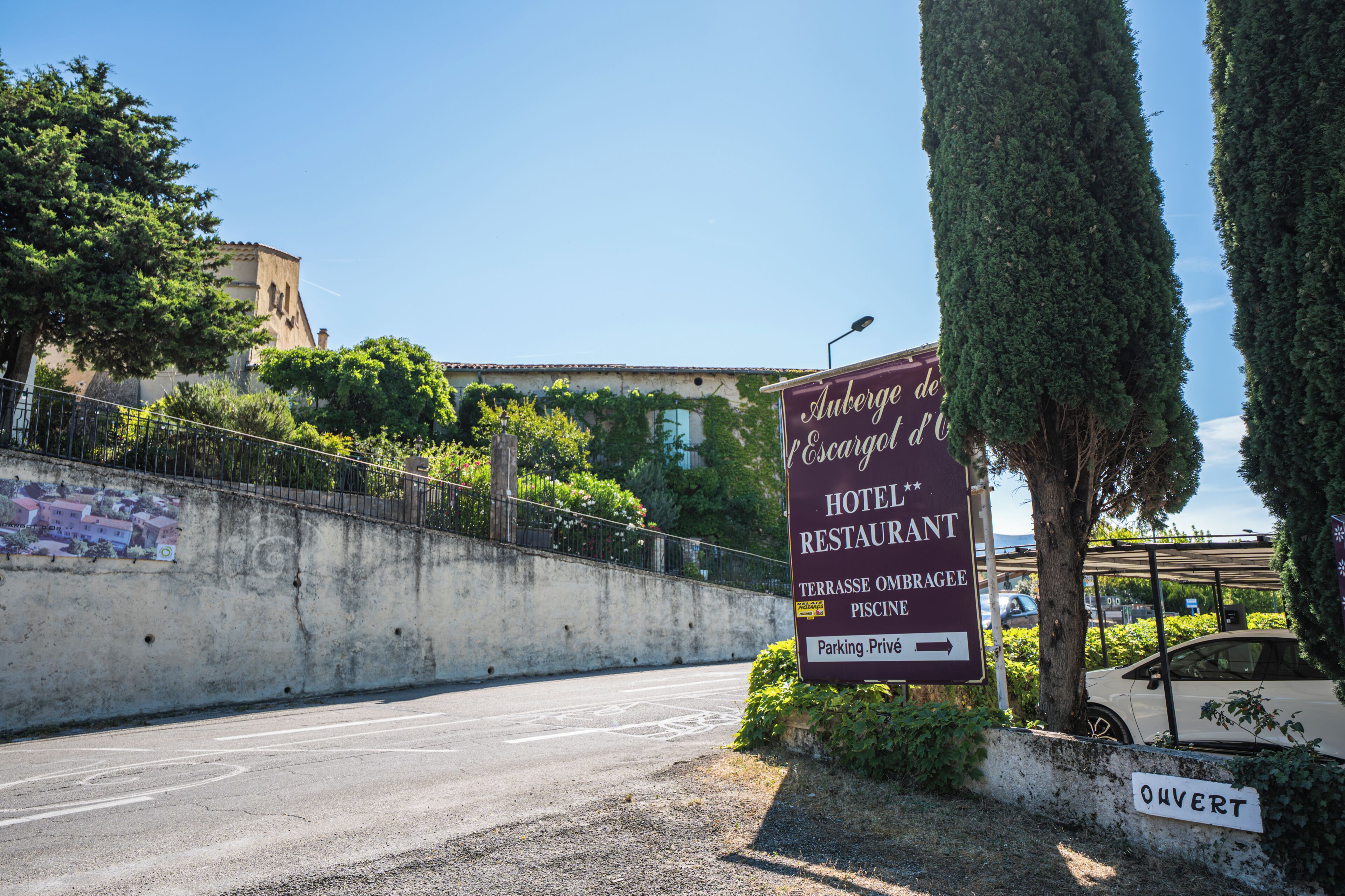A sign for Auberge de l'Escargot d'O, a hotel and restaurant with a private parking area.