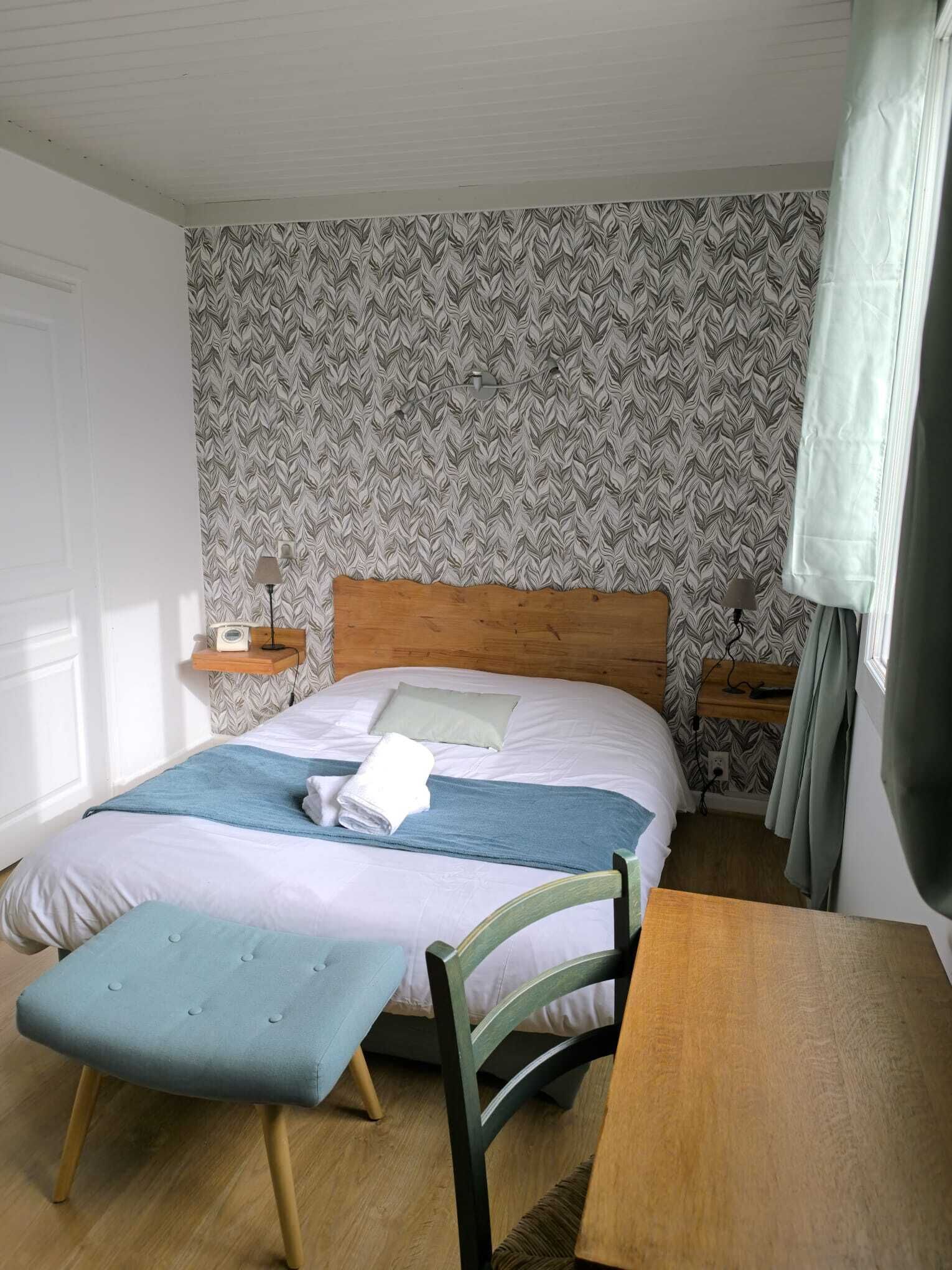 A bedroom with a bed, bedside tables, a chair, and a table.