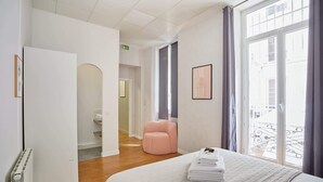 Une chambre d’hôtel avec un lit, une chaise rose, un radiateur et une fenêtre donnant sur un paysage agréable.
