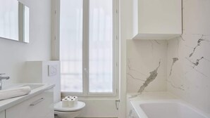 Une salle de bain moderne équipée de toilettes, d’un lavabo et d’une baignoire.