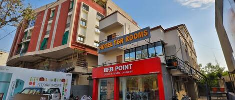 Un hôtel avec une enseigne indiquant « CHAMBRES D’HÔTEL TGR » et « POINT IFB », proposant des services d’hébergement, de cuisine et de blanchisserie.