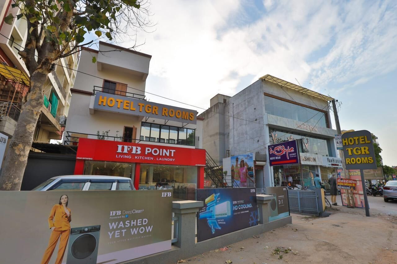A hotel named "HOTEL TGR ROOMS" with a signboard, adjacent to an IFB Point store offering kitchen, laundry, and human enterprise services.