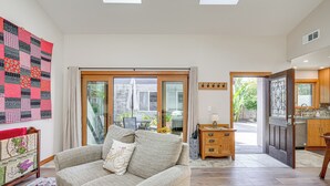 A living room with a sofa, a quilt, and a view to the outside. - Alameda Studio w/ Patio: 3 Mi to Oakland Coliseum! (Alameda)