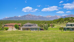 Zona residencial con casas, campos verdes y montañas al fondo.