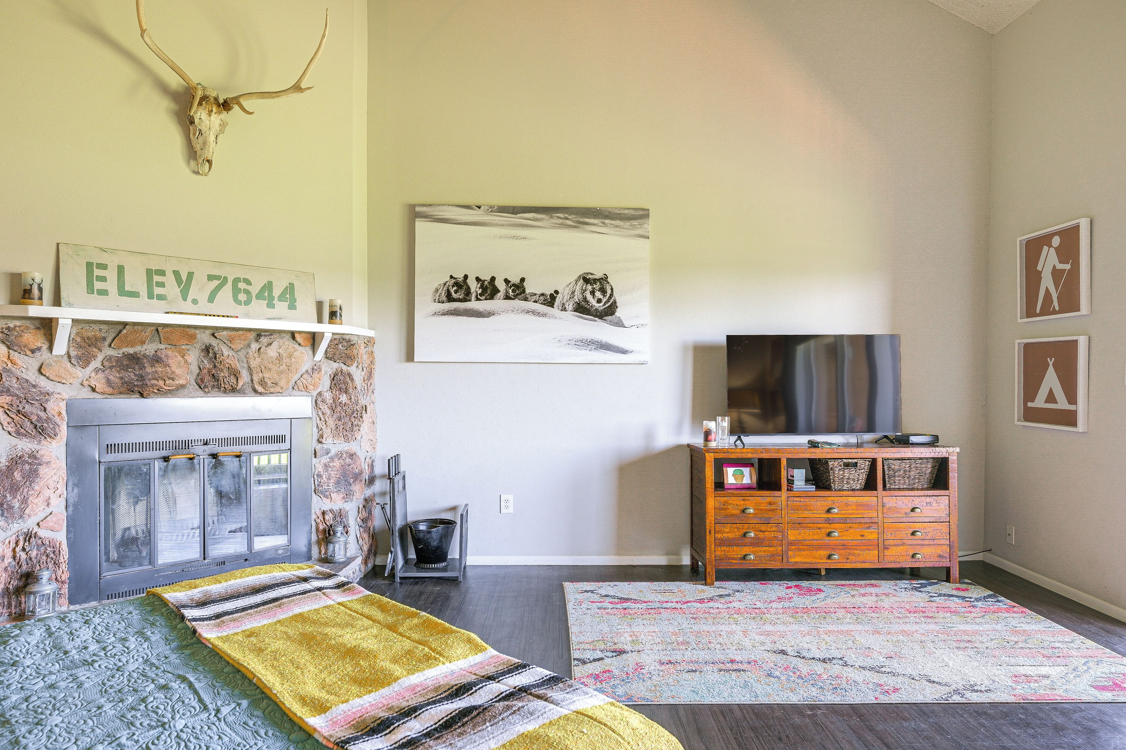 Ein Wohnzimmer mit Kamin aus Stein, einem Fernseher auf einem Holzschrank und einem Teppich.