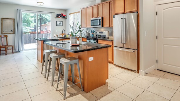 A modern kitchen with wooden cabinets, stainless steel appliances, and a central island with bar stools.