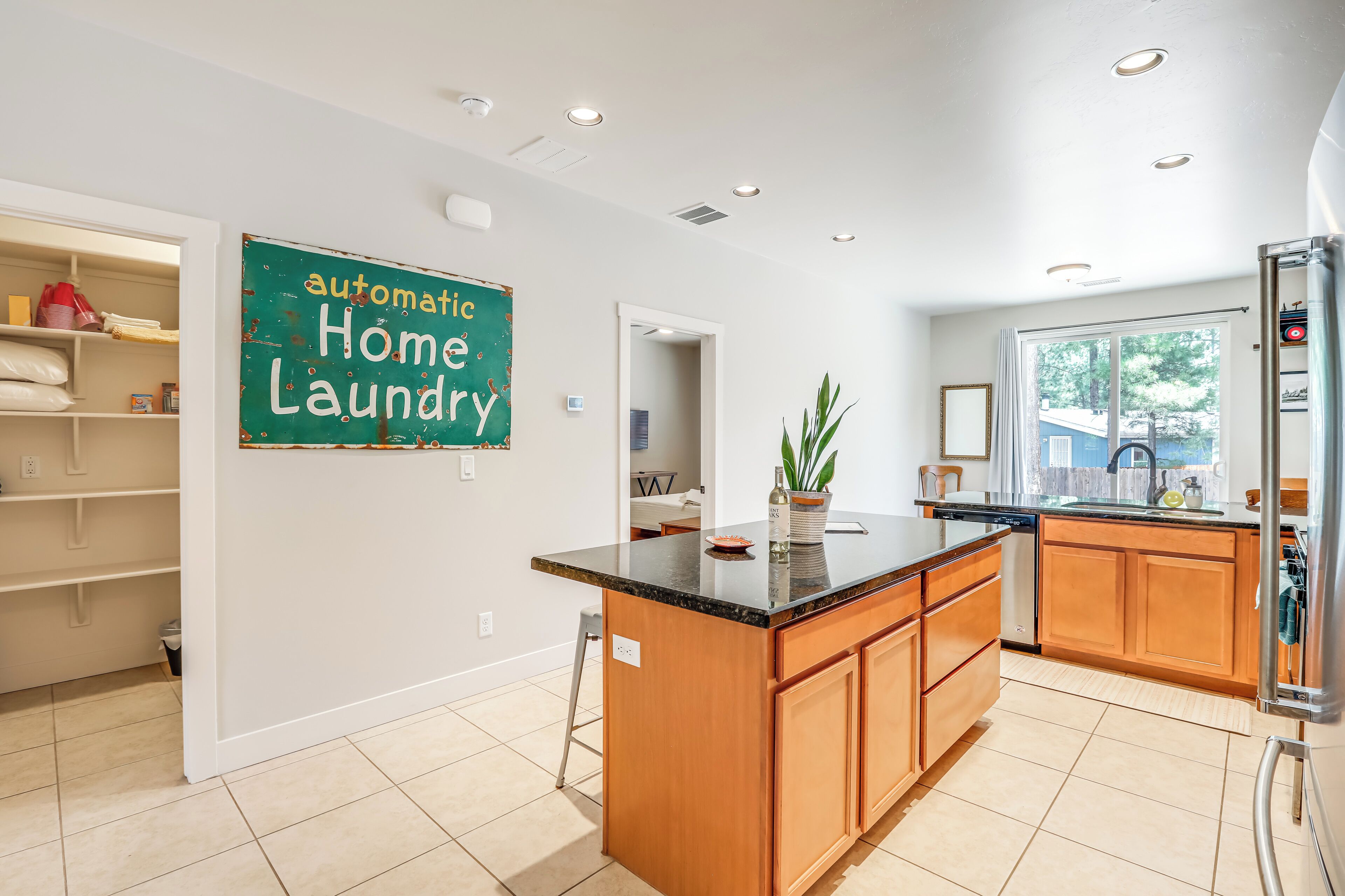 Una cucina moderna con isola centrale, mobili in legno e un cartello che riporta la scritta 'automatic home laundry'.