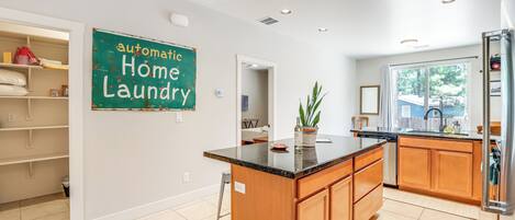 A modern kitchen with a central island, wooden cabinets, and a sign that reads "automatic home laundry."