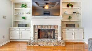 A living room with a fireplace, white cabinetry, and a flat-screen TV mounted above it. - Mobile Townhome Near University of South Alabama! (Mobile)