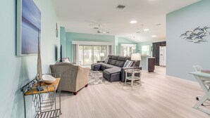 A spacious living room with a sectional sofa, a small round table, and a dining area with a white table and chairs. - Golf Cart & Pool Access: The Villages Home! (Wildwood)