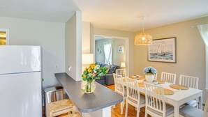 A compact kitchen with a refrigerator, a small sink, and a dining area with a table and chairs.